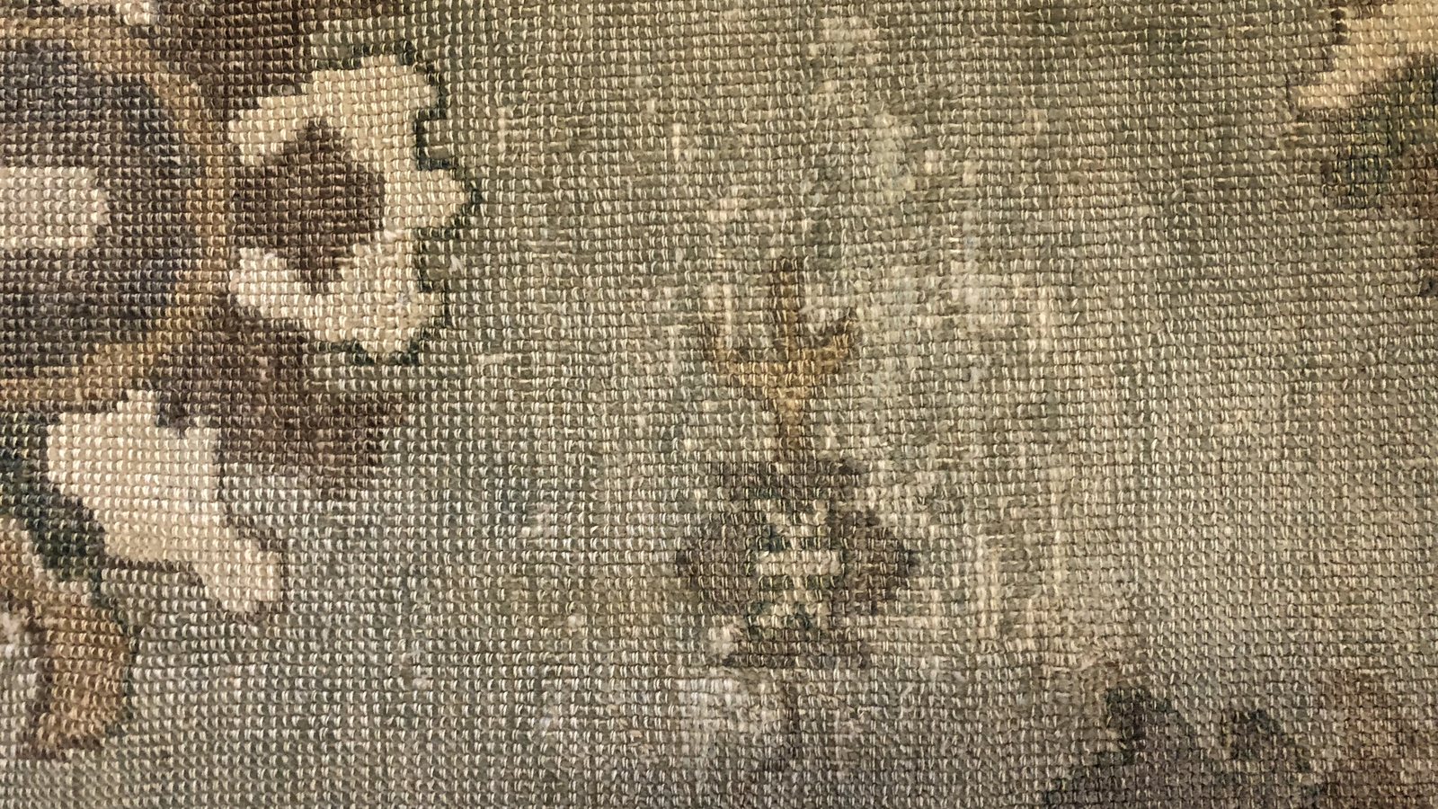 The reverse of a wool rug, where humidity damage in the foundation shows before the pile gives it away